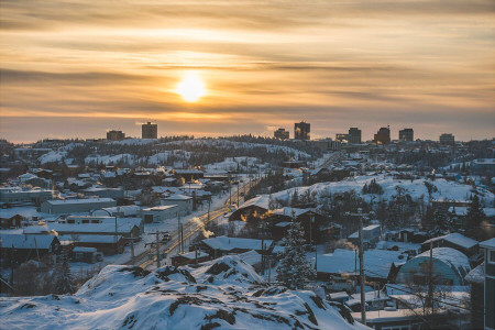 a town blanketed in snow with the sun rising