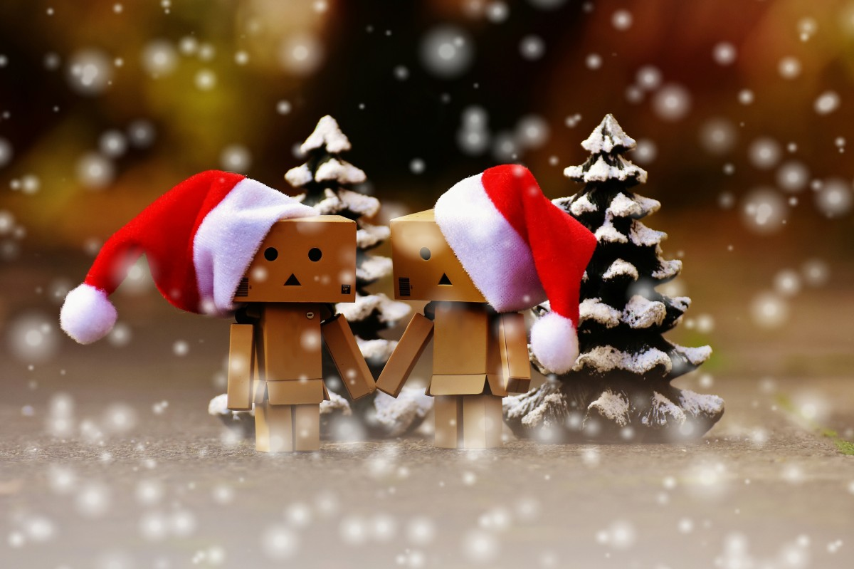 Two cardboard robots wearing santa hats in the snow